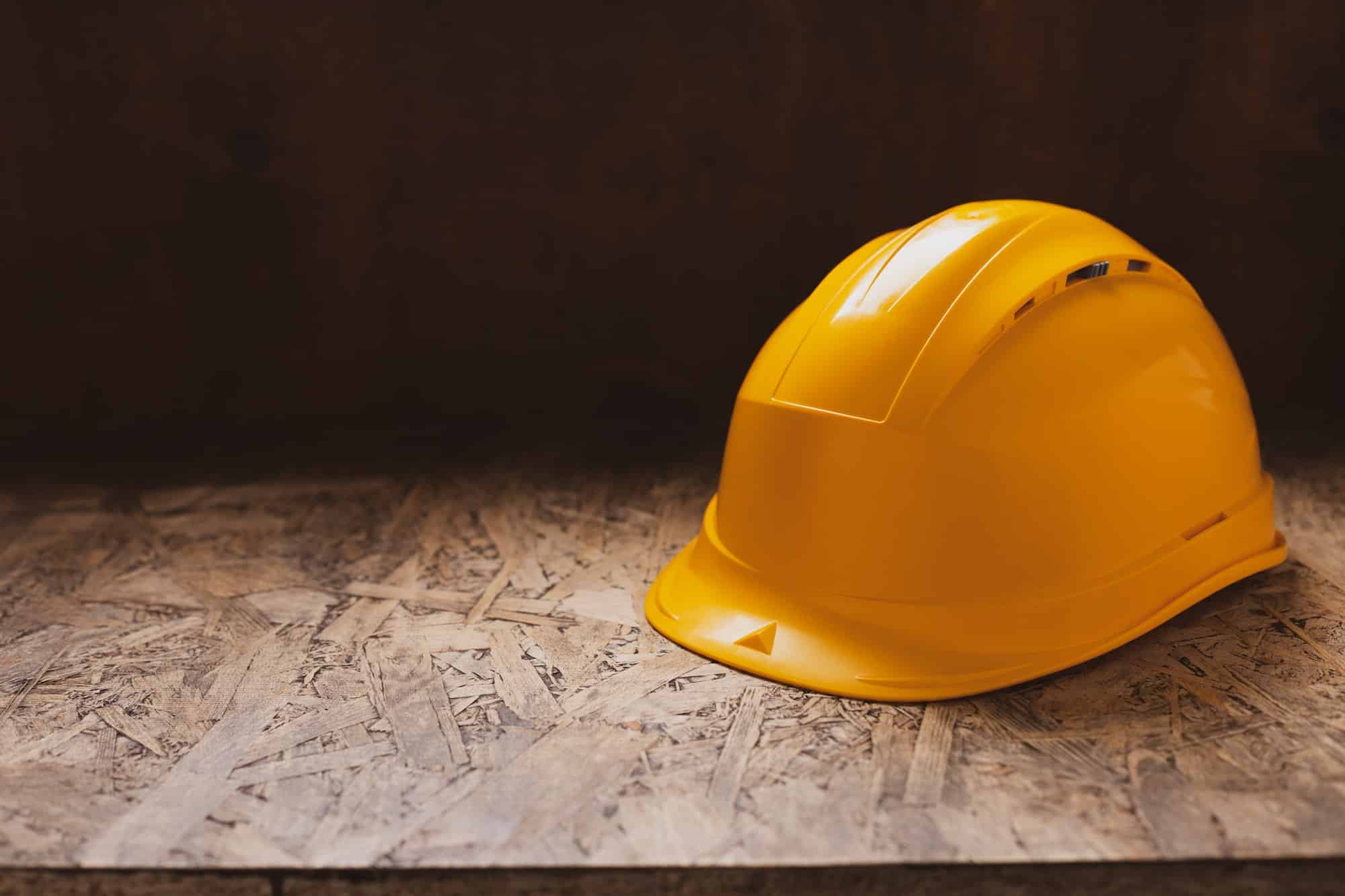 Construction helmet at wooden table background texture. Work cap and concept of renovation