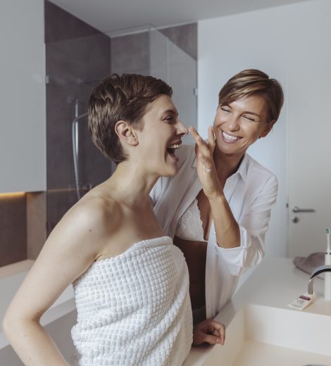 Happy lesbian couple getting ready for their day in the bathroom